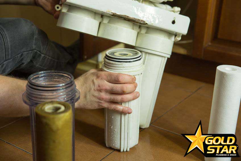Changing filters in your home water purification system. The master replaces the gut filter in the coal system.